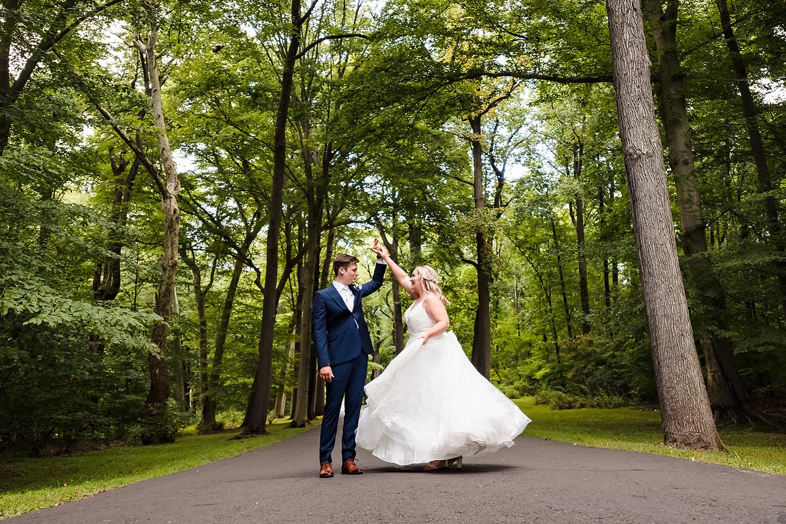 Bride and groom pose under a tree path for a romantic wedding photo.