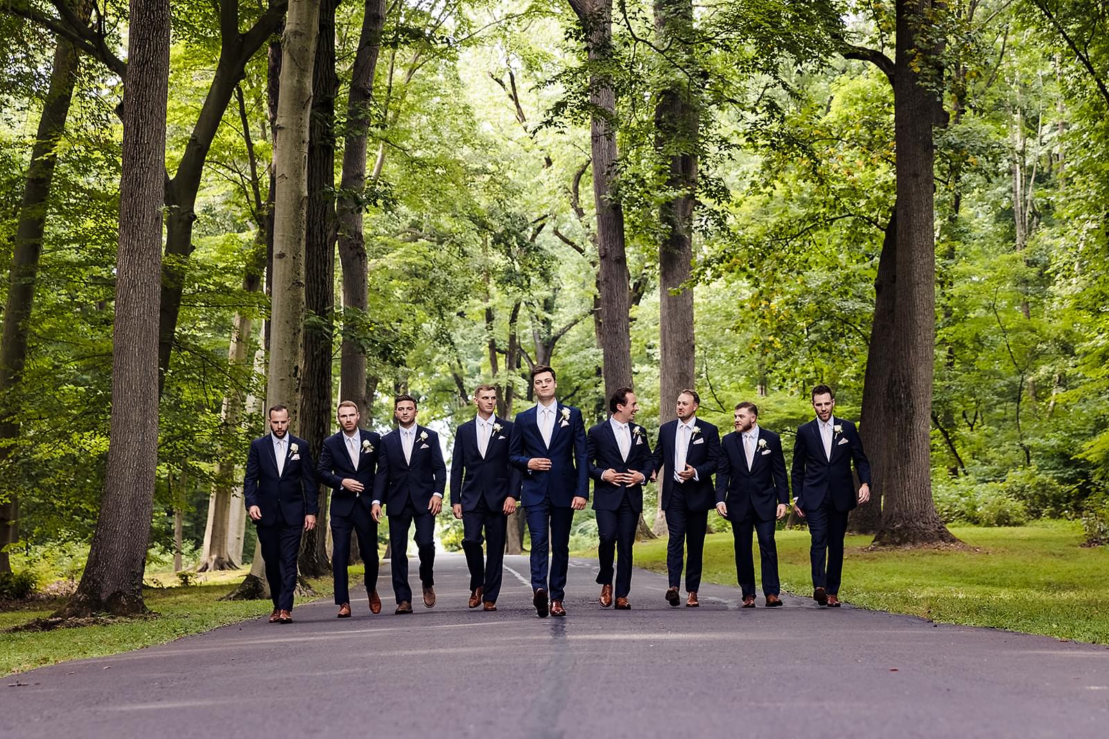 Outdoor wedding photo of groom and groomsmen walking on a path.