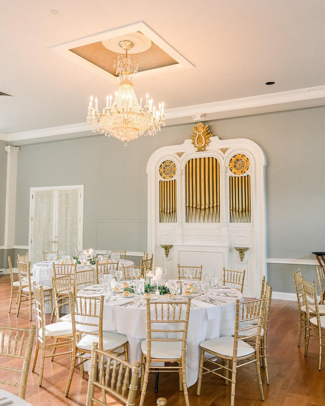Wedding ballroom with round tables and decorative with large chandelier.